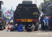 Beberapa massa aksi dari Konfederasi Serikat Persatuan Seluruh Indonesia (KSPSI) beristirahat di bawah kendaraan petugas kepolisian di depan gedung DPR/MPR RI,Jakarta, Rabu (12/2)