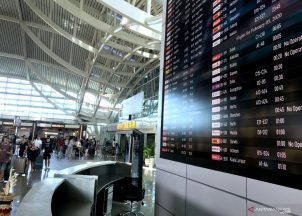 Penumpang melintas di dekat layar informasi penerbangan di Terminal Keberangkatan Internasional Bandara Internasional I Gusti Ngurah Rai, Bali, Selasa. Foto: ANTARA