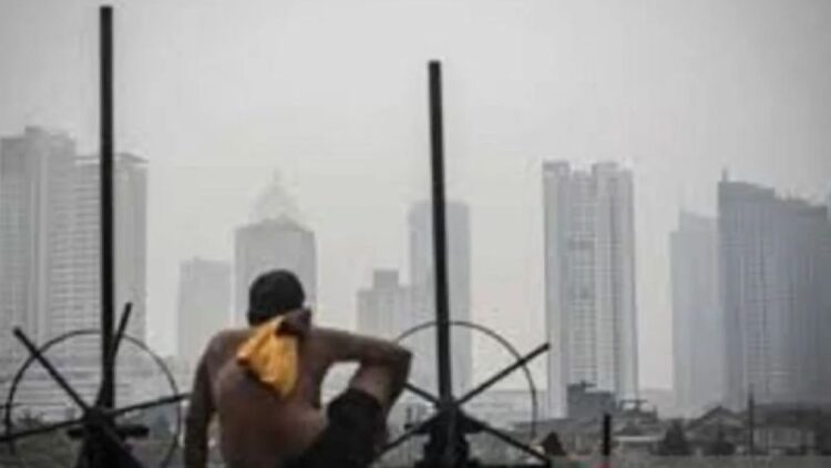 Ilustrasi - Seorang warga berjemur dengan latar belakang gedung bertingkat tersamar kabut polusi udara di Jakarta. ANTARA