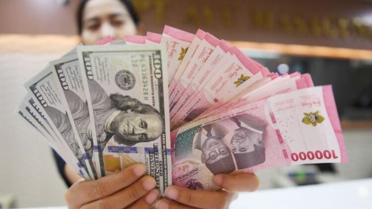 Petugas menunjukkan mata uang rupiah dan dolar AS di Ayu Masagung Money Changer, Jakarta.Dok. Antara