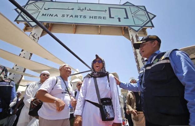 Kabid Linjam PPIH Arab Saudi Harun Arrasyid (kanan) berbincang dengan jamaah haji Indonesia saat antre menuju bus di kawasan tenda Mina, Makkah, Arab Saudi, Minggu (8/6/2025). ANTARA FOTO/Andika Wahyu/YU